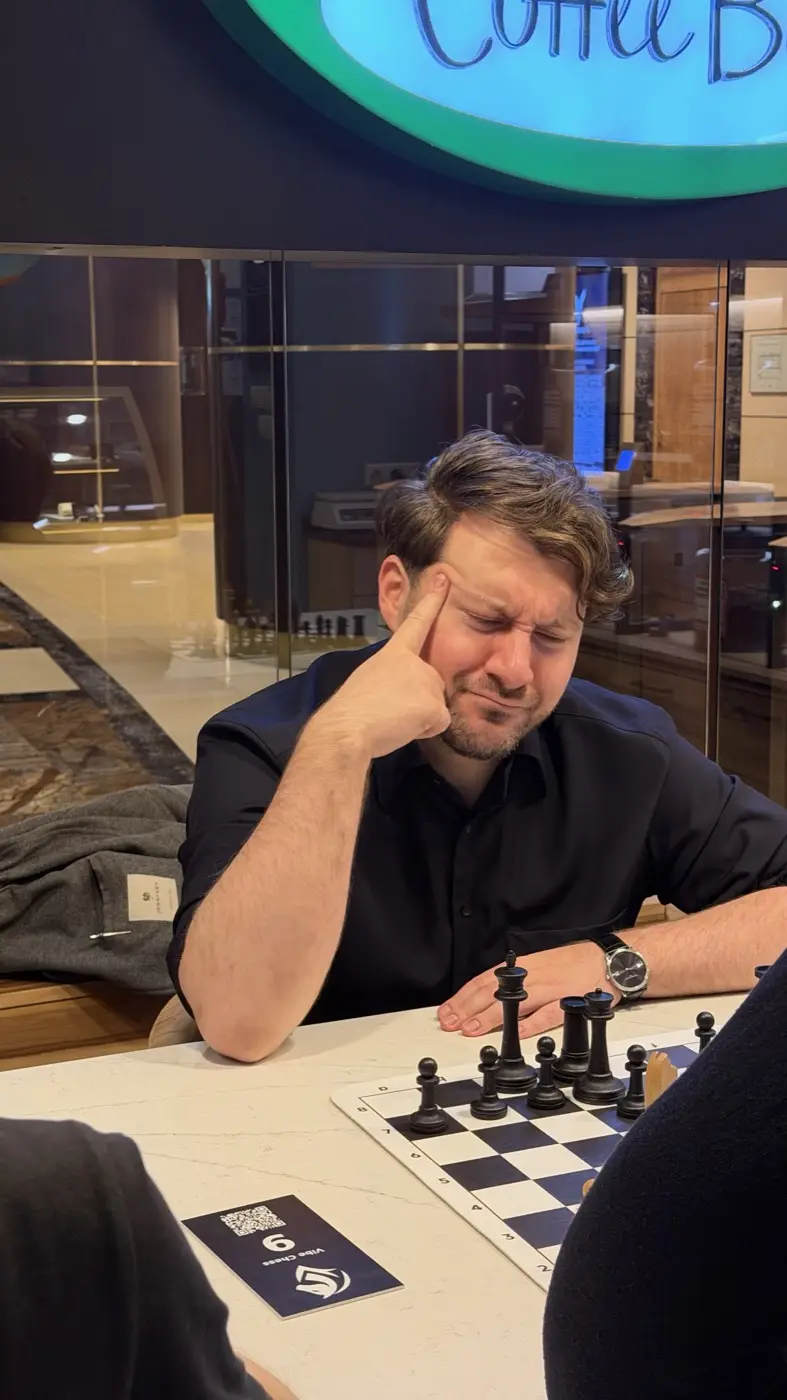 A tournament player at Coffee Bean thinking over a move, head resting on his hand