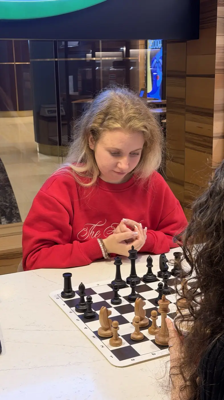 A tournament player in a red sweater looking at the board