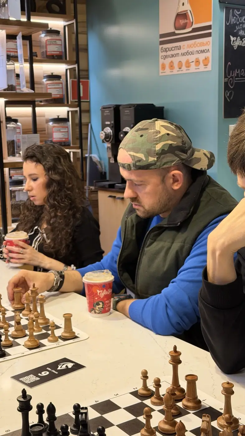 Two people playing a game at a small table in Coffee Bean, coffee cups beside the board