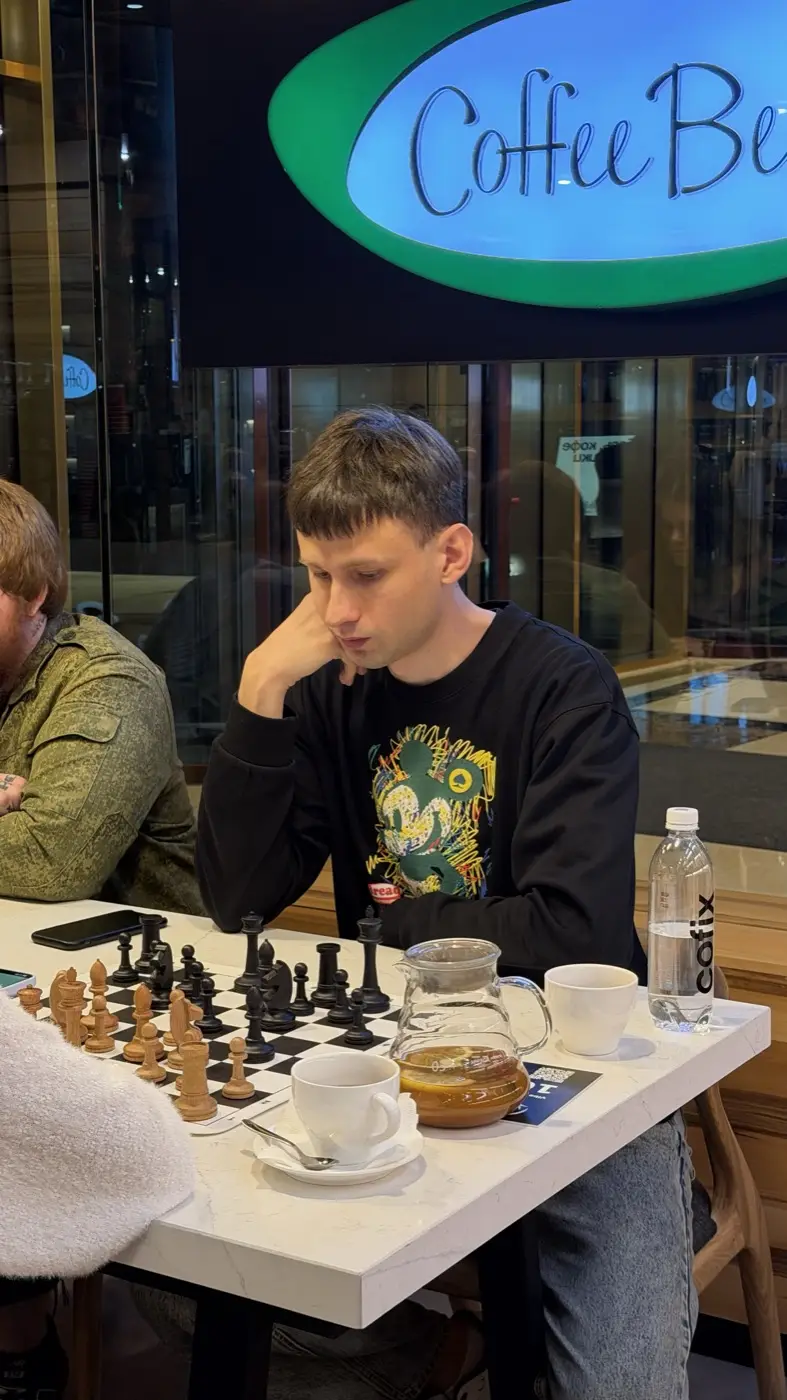 A young player over a board with wooden pieces, a cup of coffee next to it