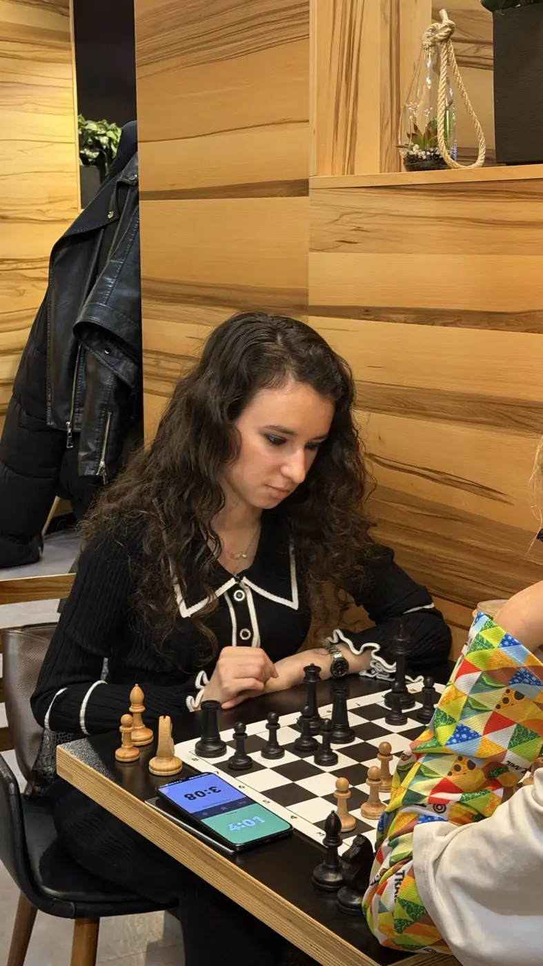 A player making a move, a phone with the chess clock beside the board