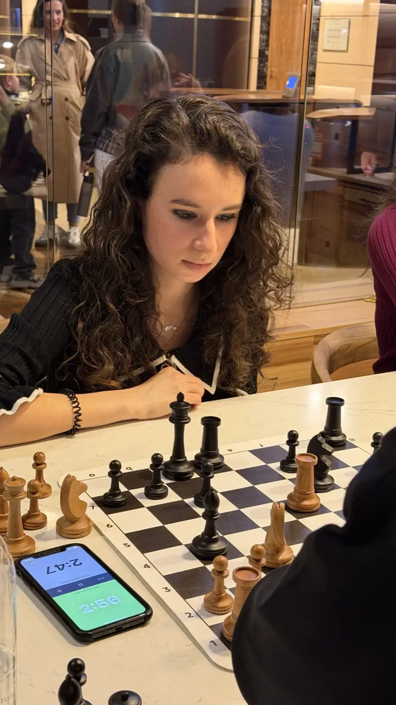 A tournament player over the board, a phone with the app's clock on the table