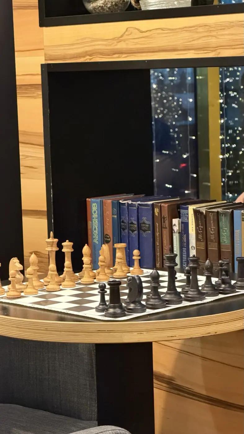 Close-up of wooden chess pieces against a row of book spines