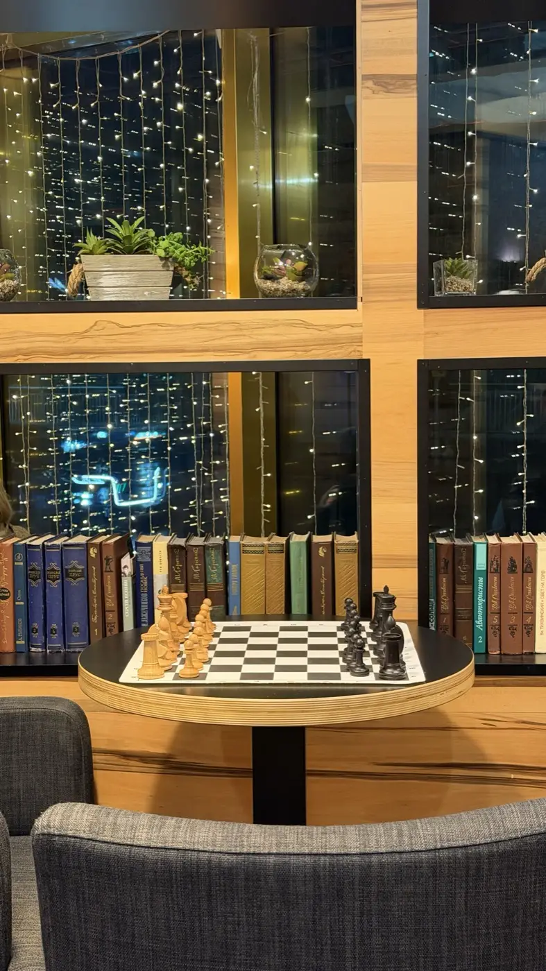 A table with a board by a window overlooking the Moscow City towers