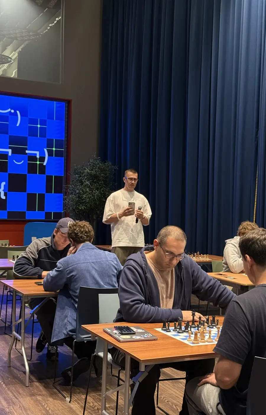 A round in progress: several boards with games, the host standing by the screen