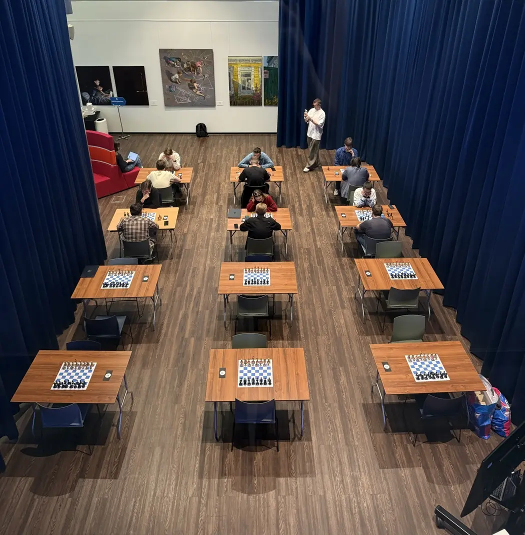 Corporate chess tournament hall: rows of tables with boards and clocks, games in progress
