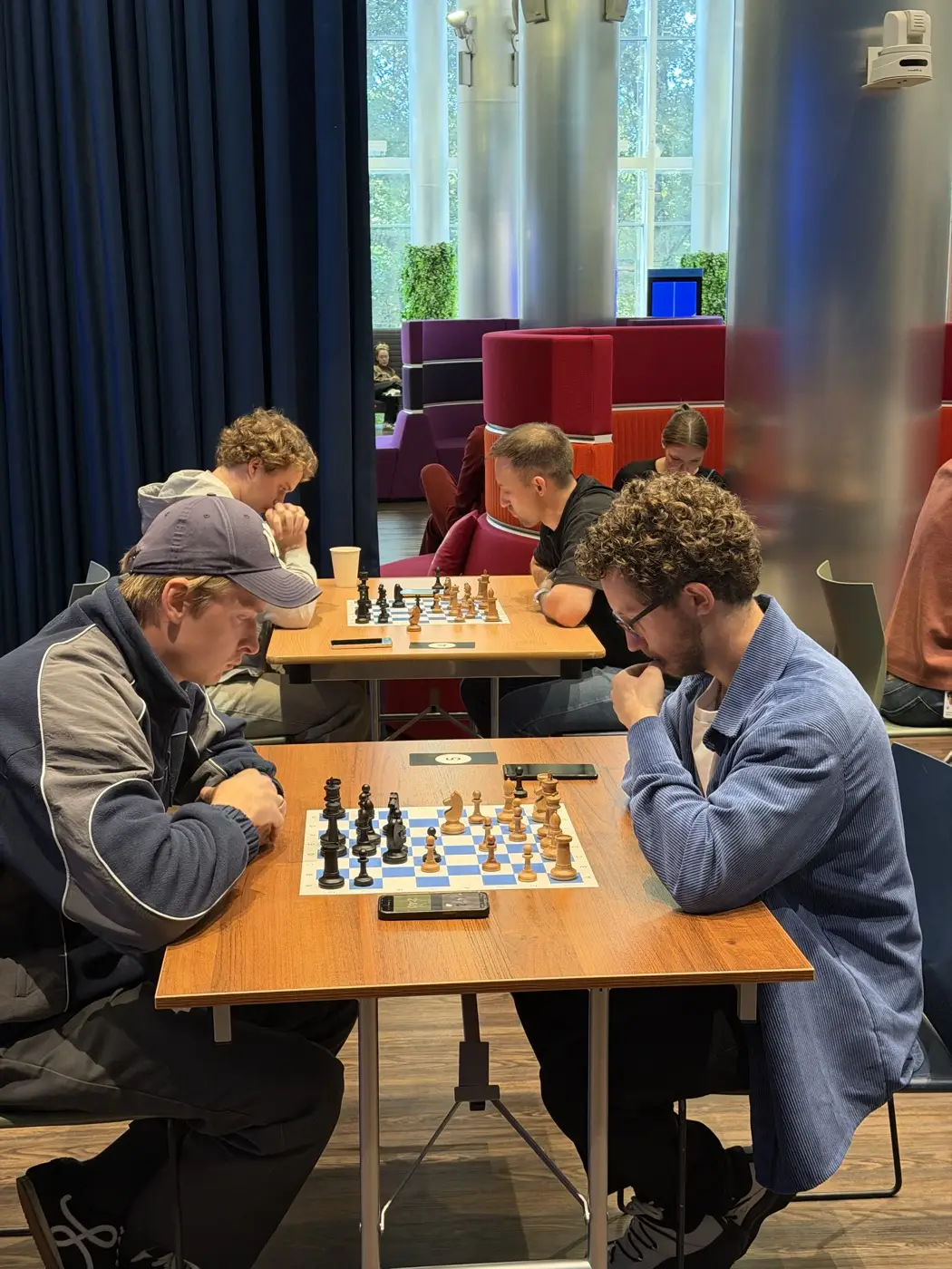 A game at a corporate tournament: players at the table, an endgame on the board