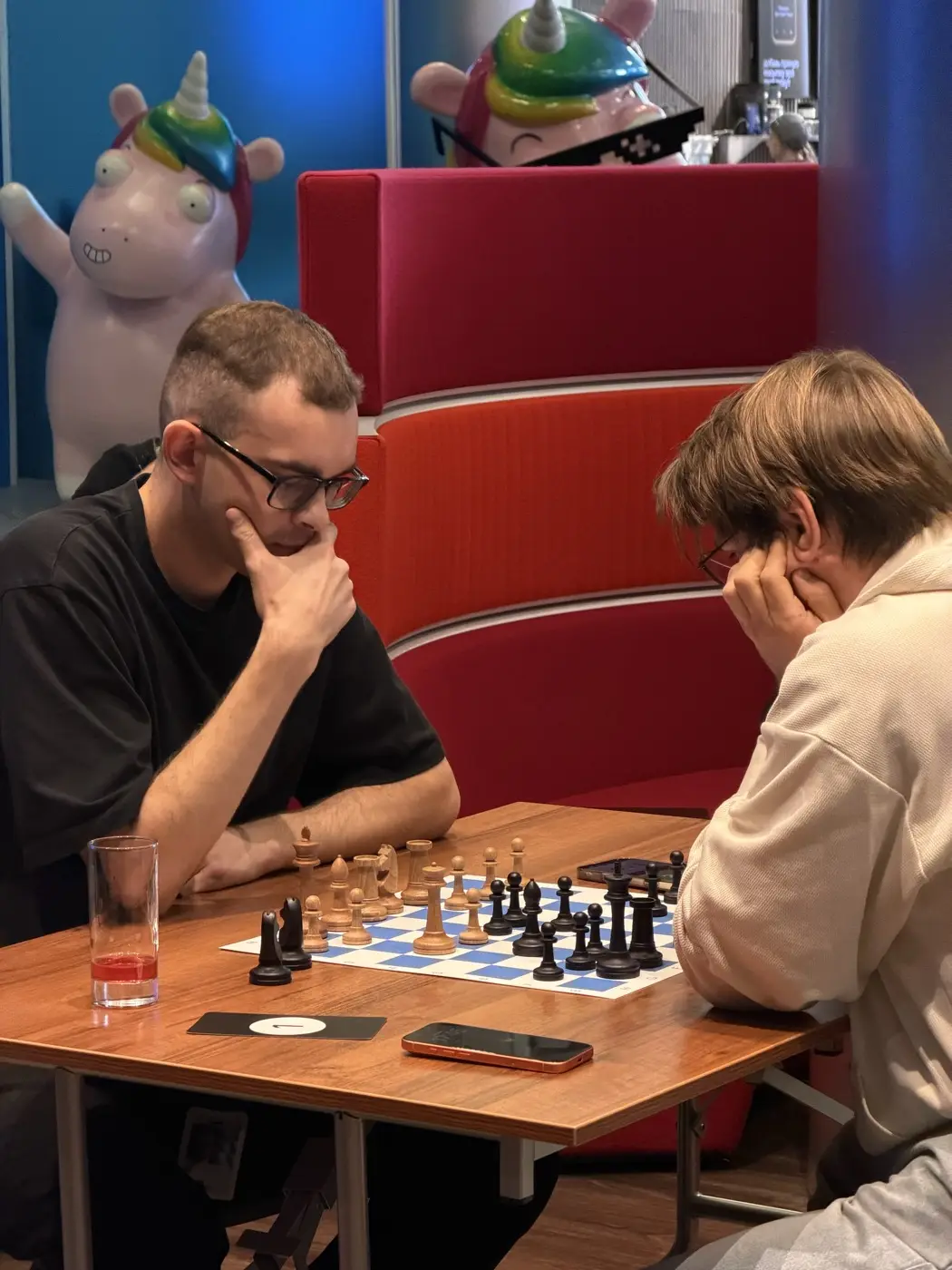 Two players thinking over the position, a chess clock next to the board