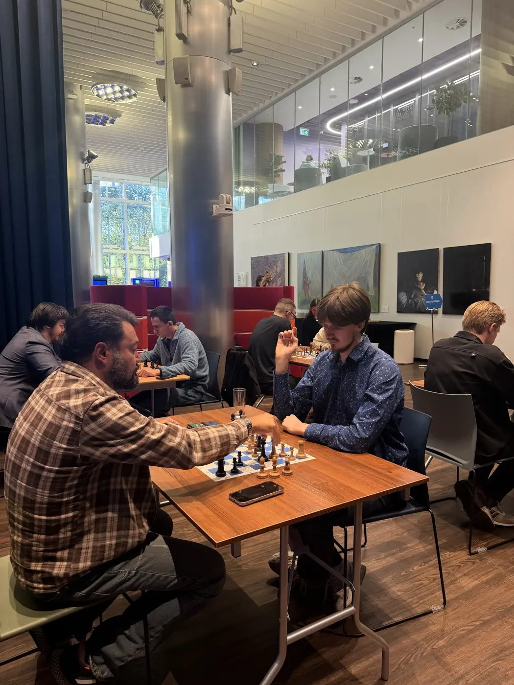 Chess tournament in an office space: tables with boards set between the columns