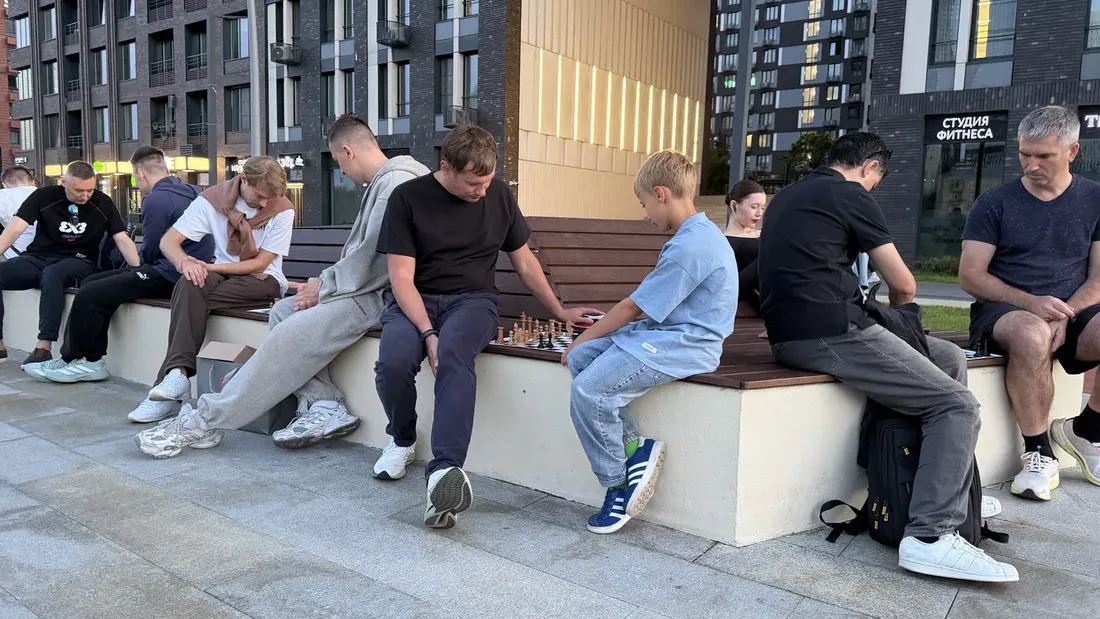 Several pairs playing chess on a bench on the embankment