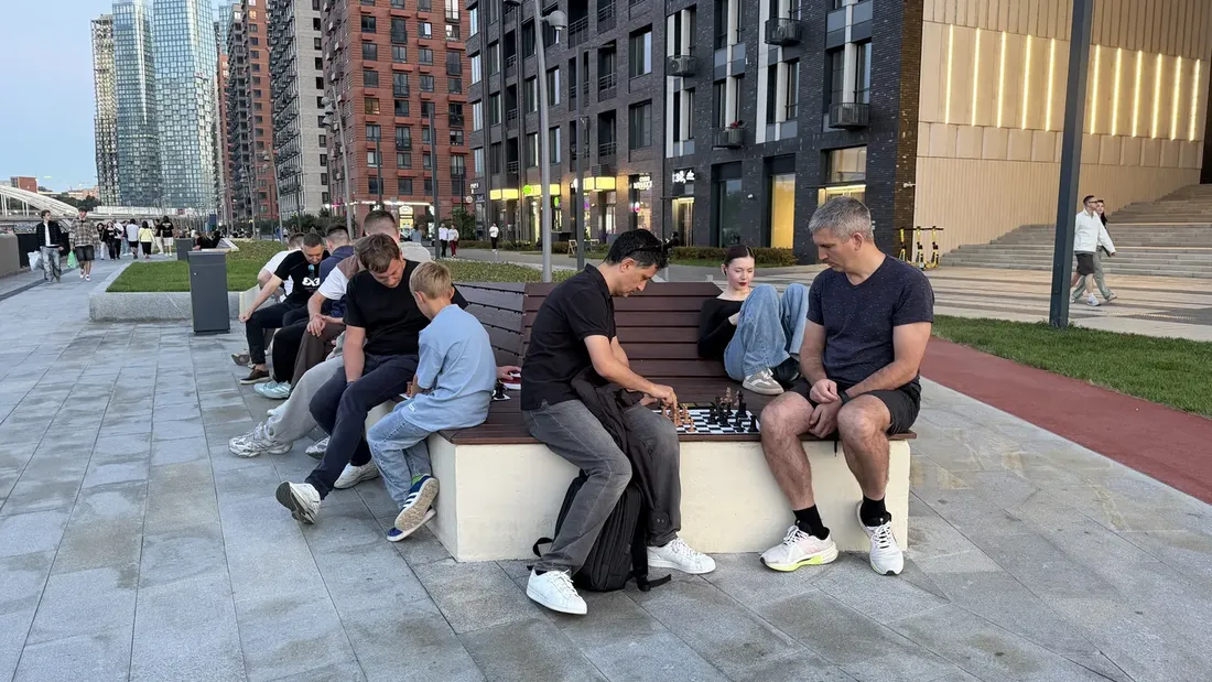 A group playing chess on the embankment in the evening
