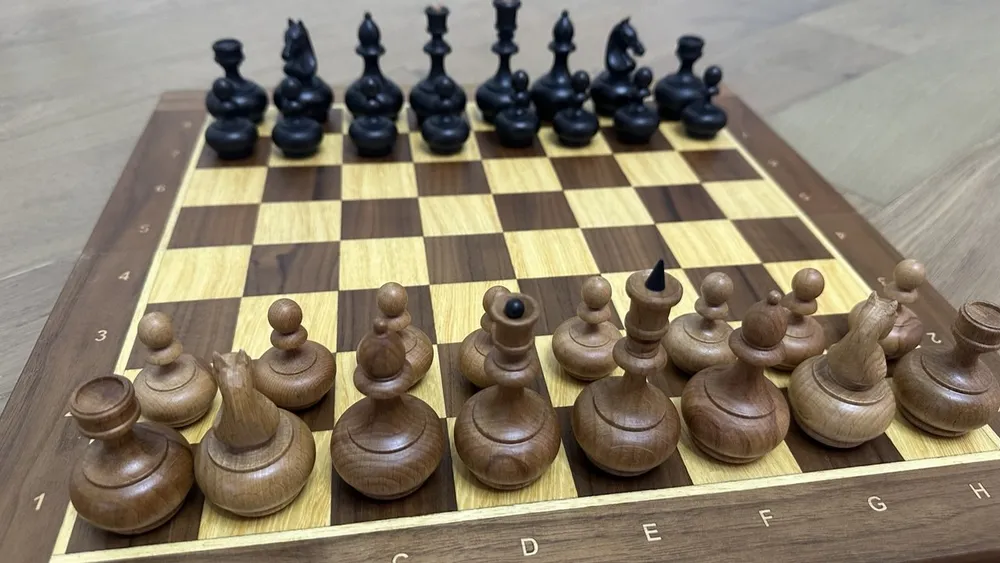 The chess pieces set up on a wooden board - the view from White's side